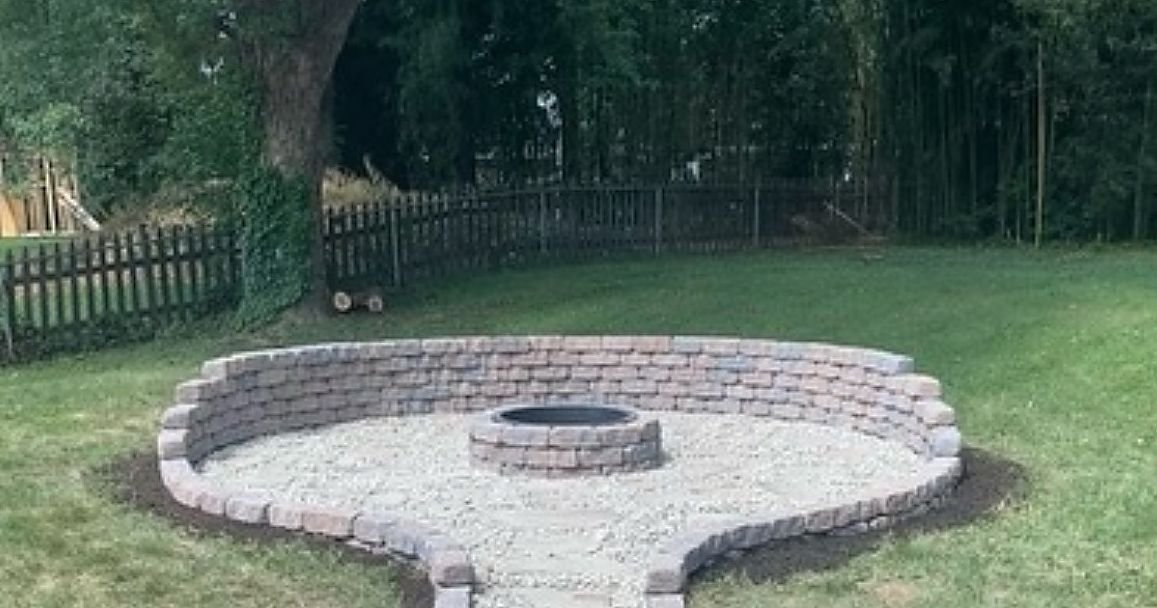 A fire pit is sitting in the middle of a lush green yard.