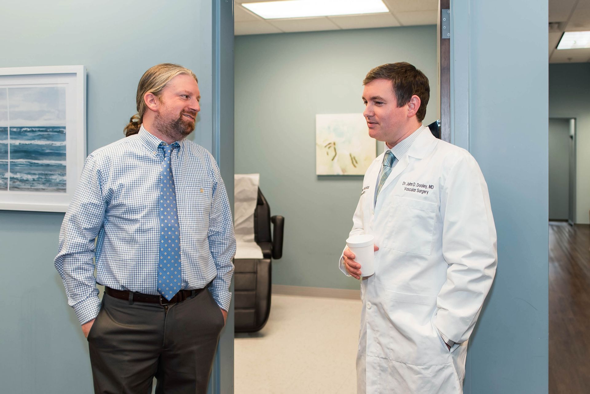 A doctor is sitting at a desk talking to another doctor