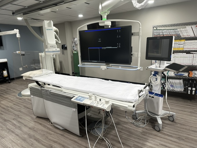A hospital room with a large monitor on top of a bed.