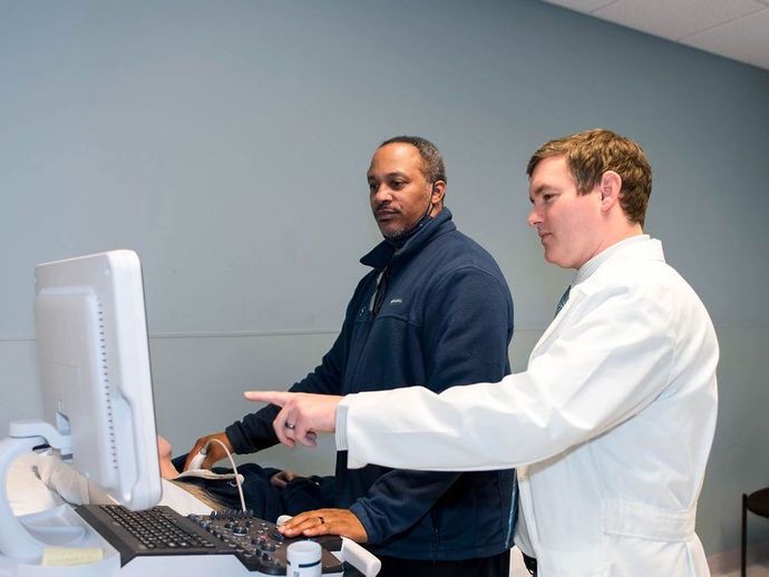 Two men in white coats are working on a computer