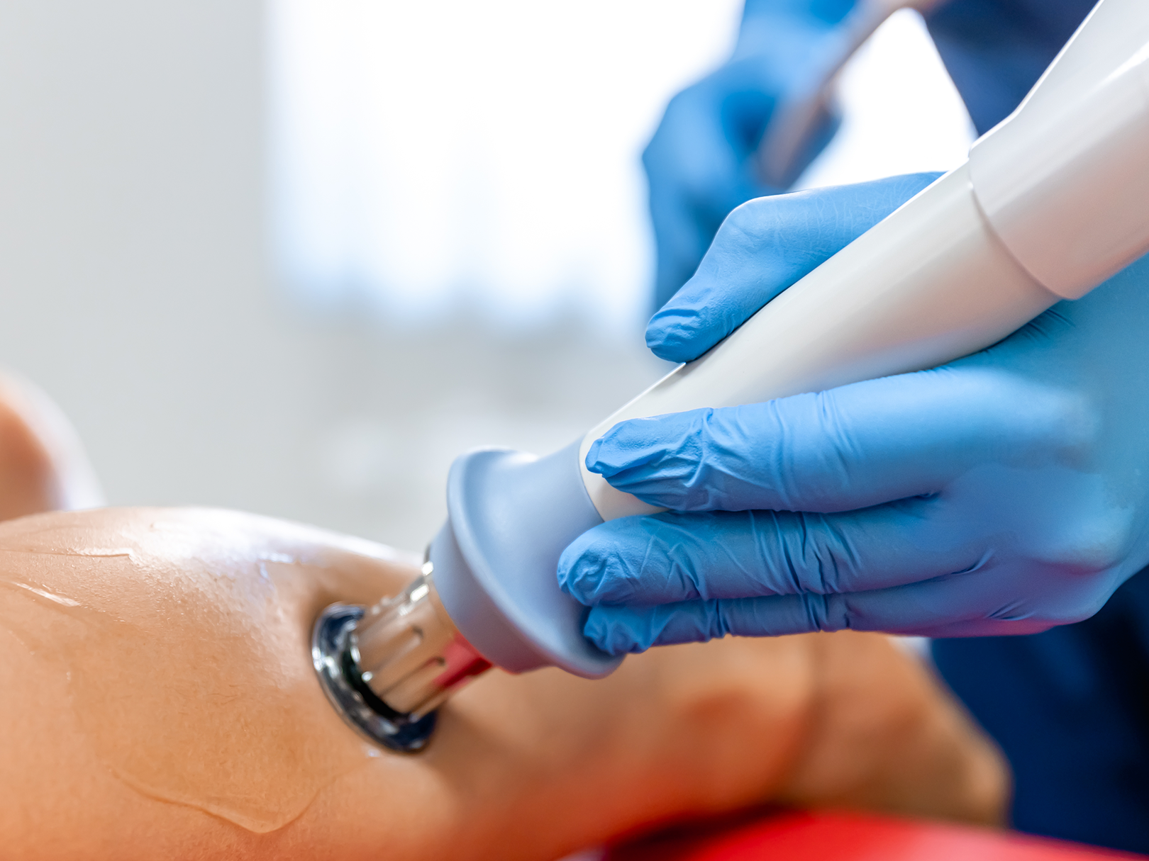 A person wearing blue gloves is using a machine on a mannequin.