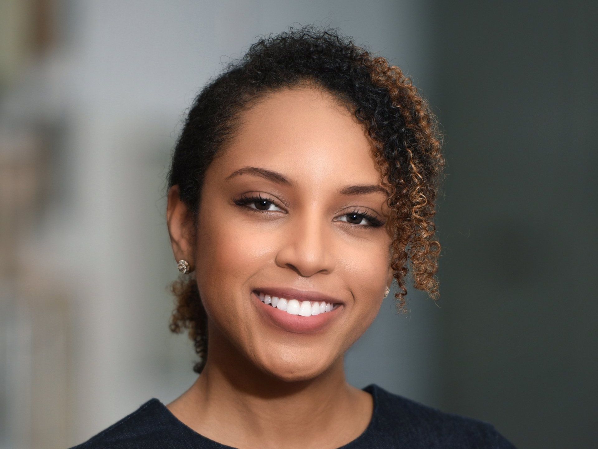 A woman with curly hair is smiling for the camera.