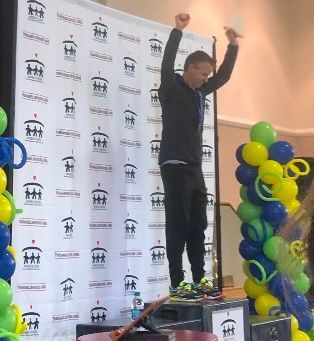 A man is standing on a podium with his arms in the air