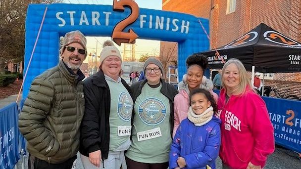 A group of people are standing in front of a start and finish sign.
