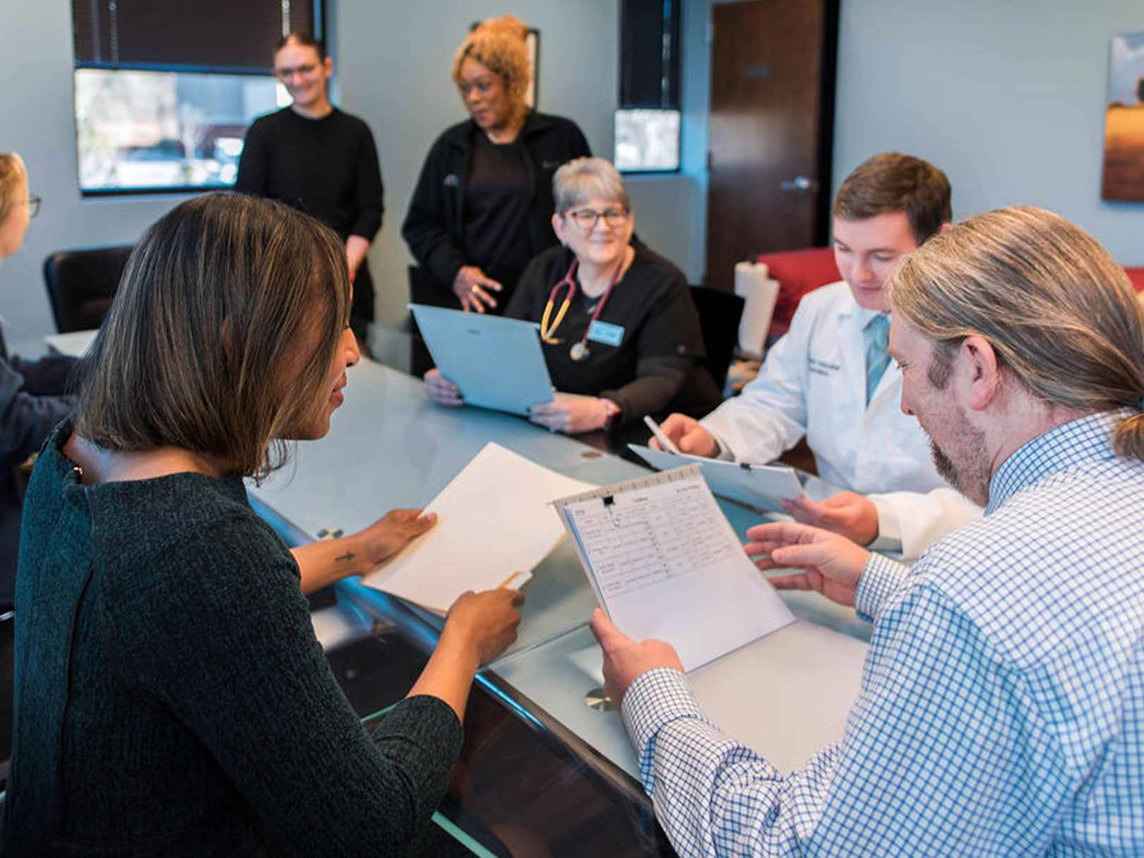 A group of people are sitting around a table looking at papers.