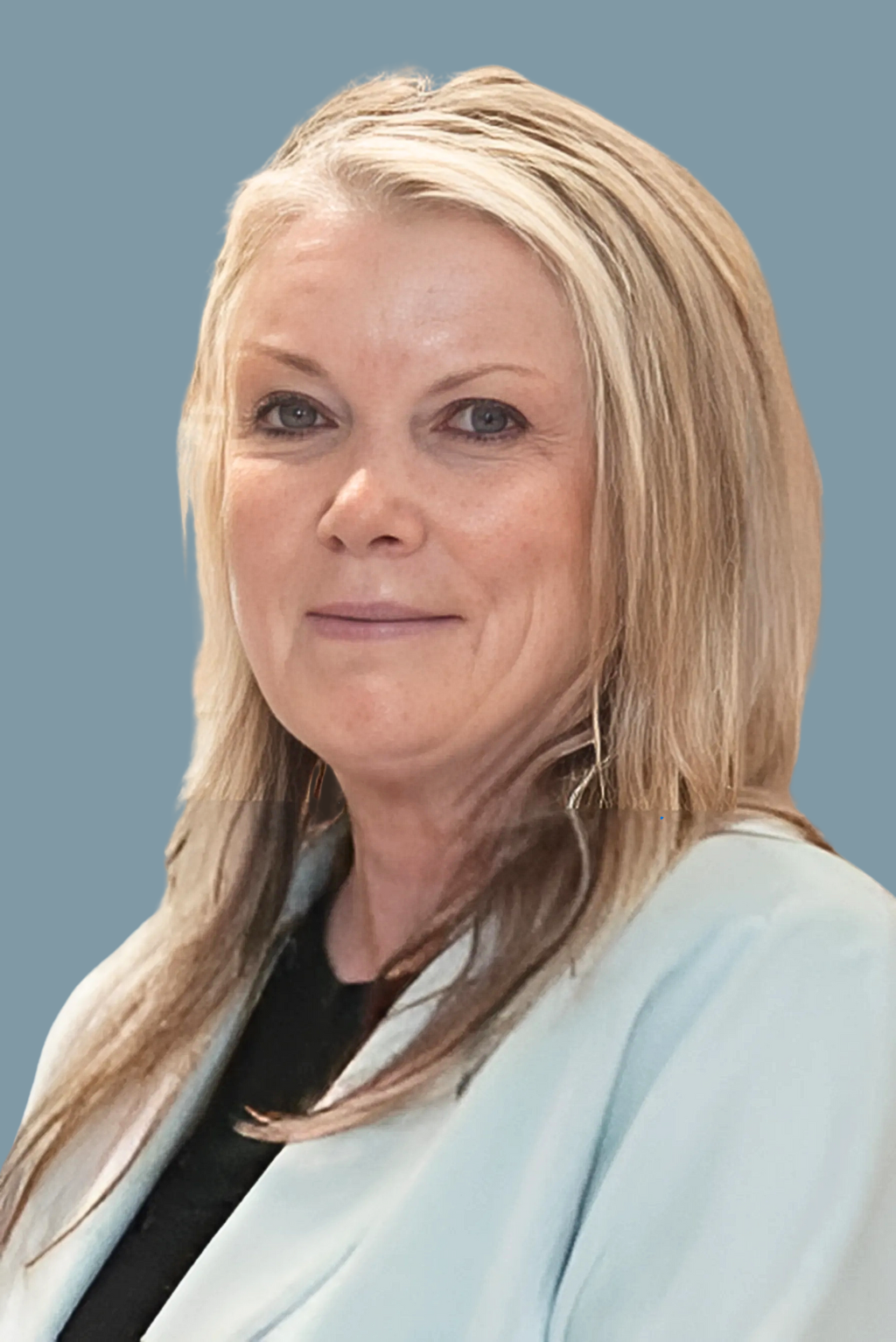 A woman with long blonde hair is wearing a blue jacket and a black shirt.