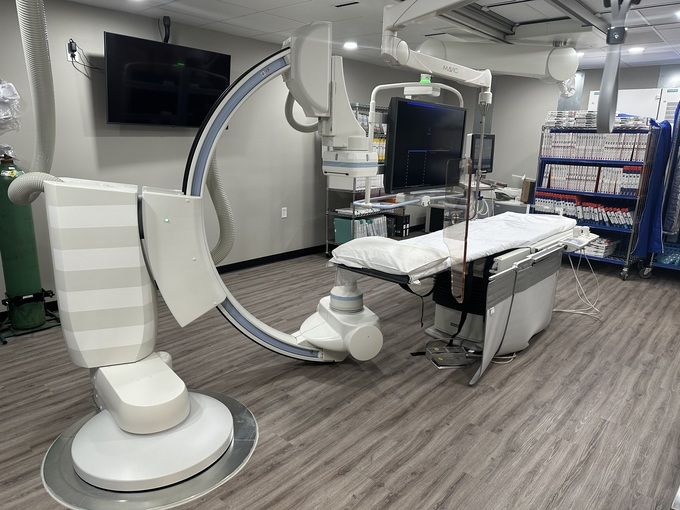 A hospital room with a large surgical machine and a bed.