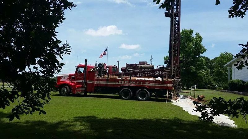 A red truck is parked in a grassy yard