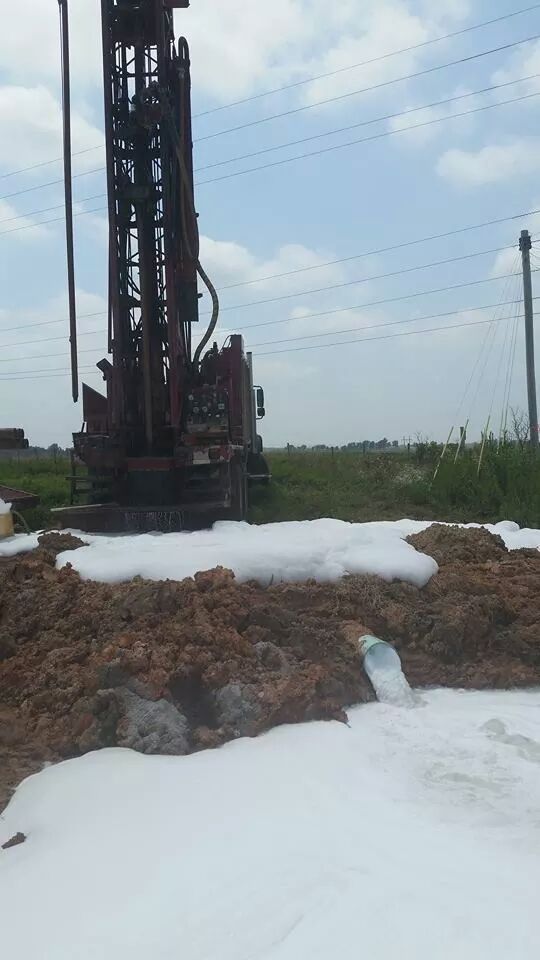 A drilling rig is sitting on top of a pile of dirt in a field.