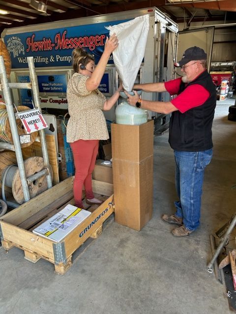 A man and a woman standing in front of a truck that says hewn-messenger