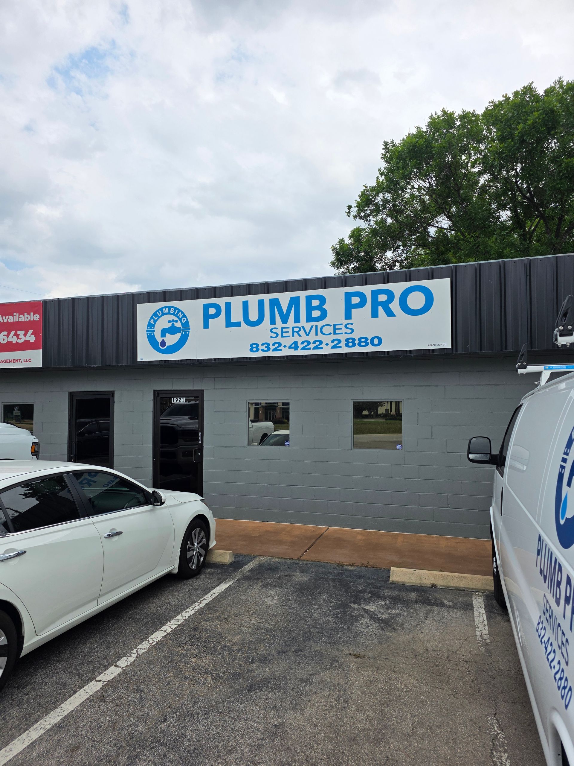 A white car is parked in front of a building that says plumb pro.