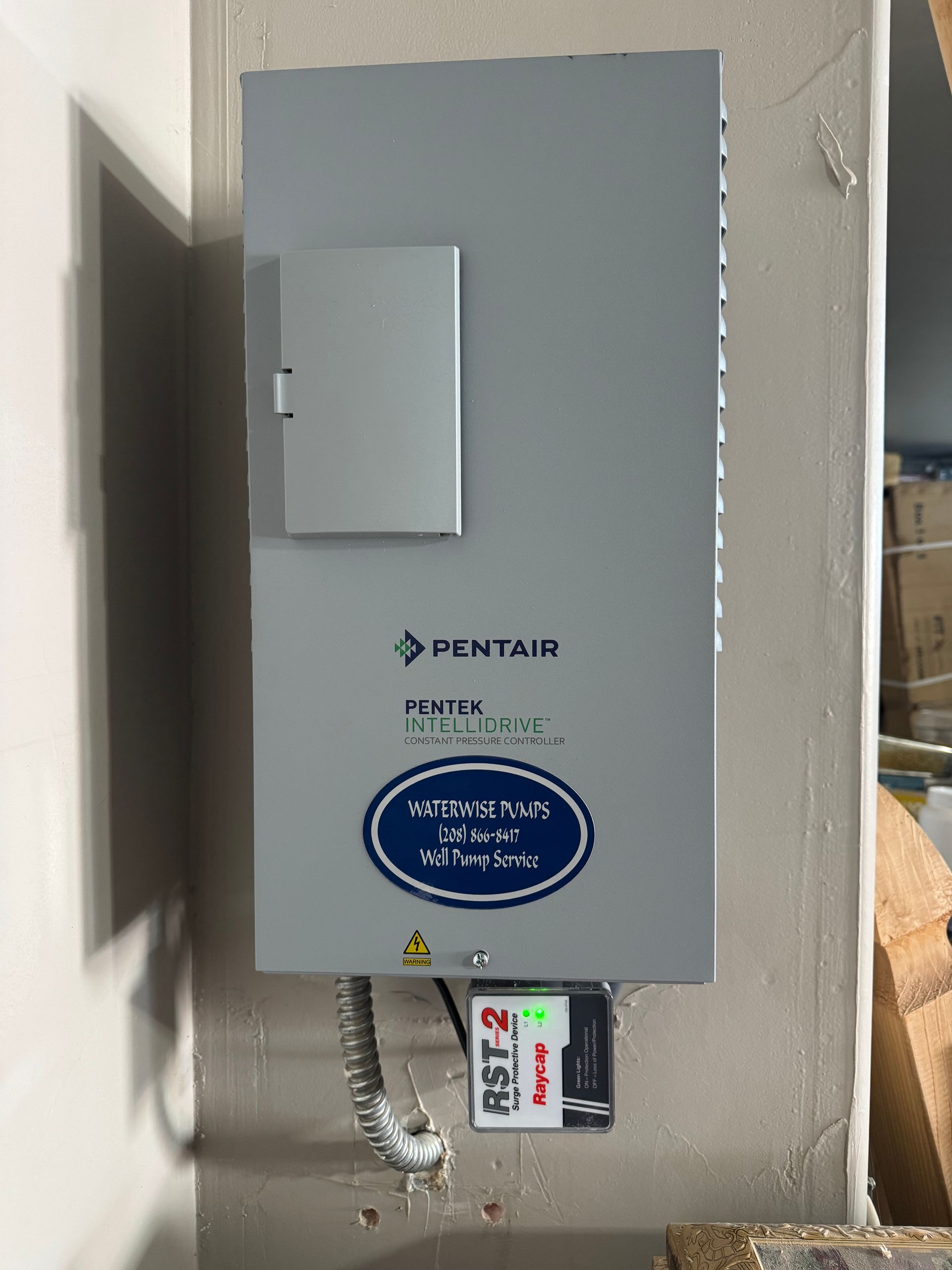 A gray Pentair pool control panel mounted on a wall with a small AST-2 time clock switch attached below.