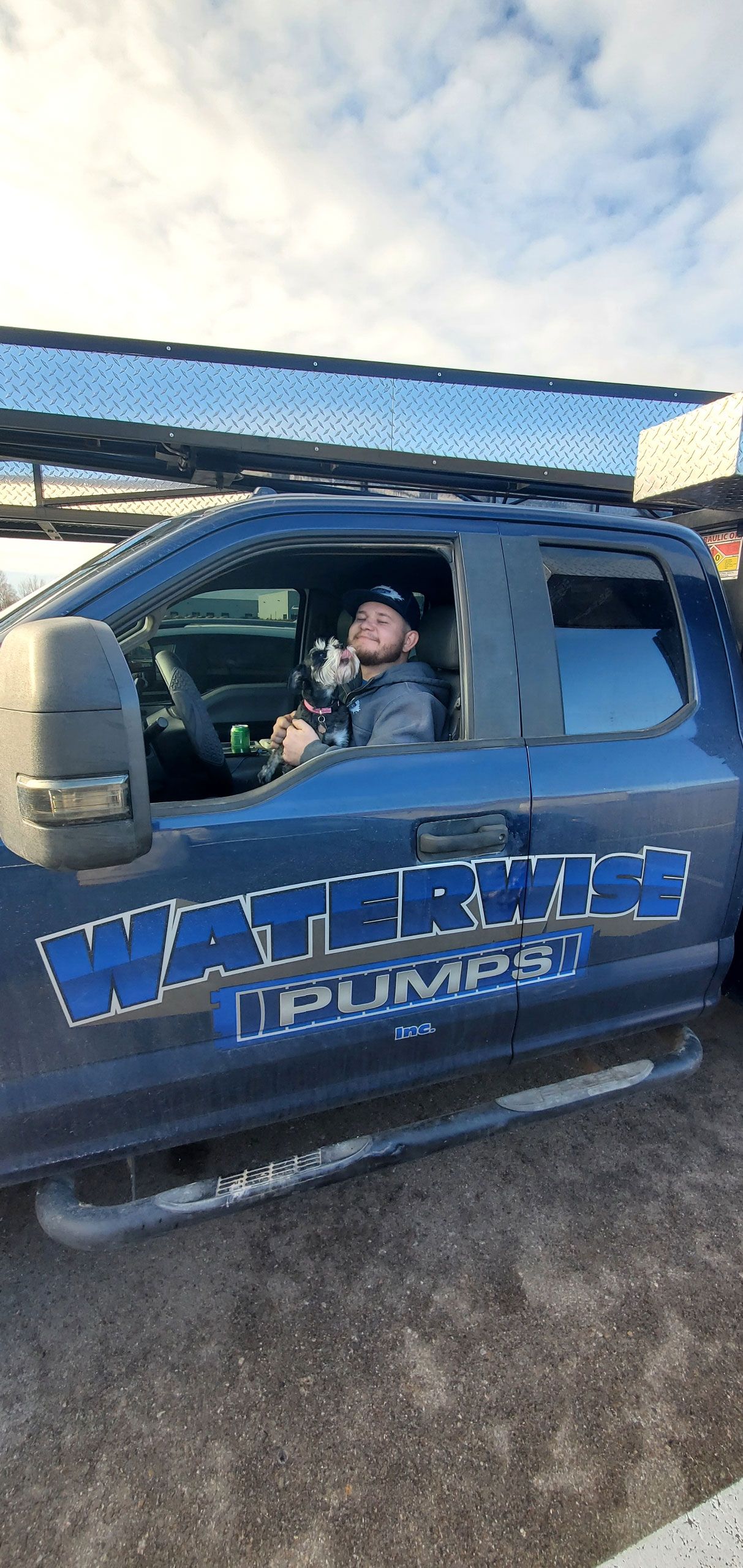 A person sits in the driver’s seat of a blue work truck marked 