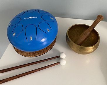 A blue drum and a brass bowl are sitting on a white table.