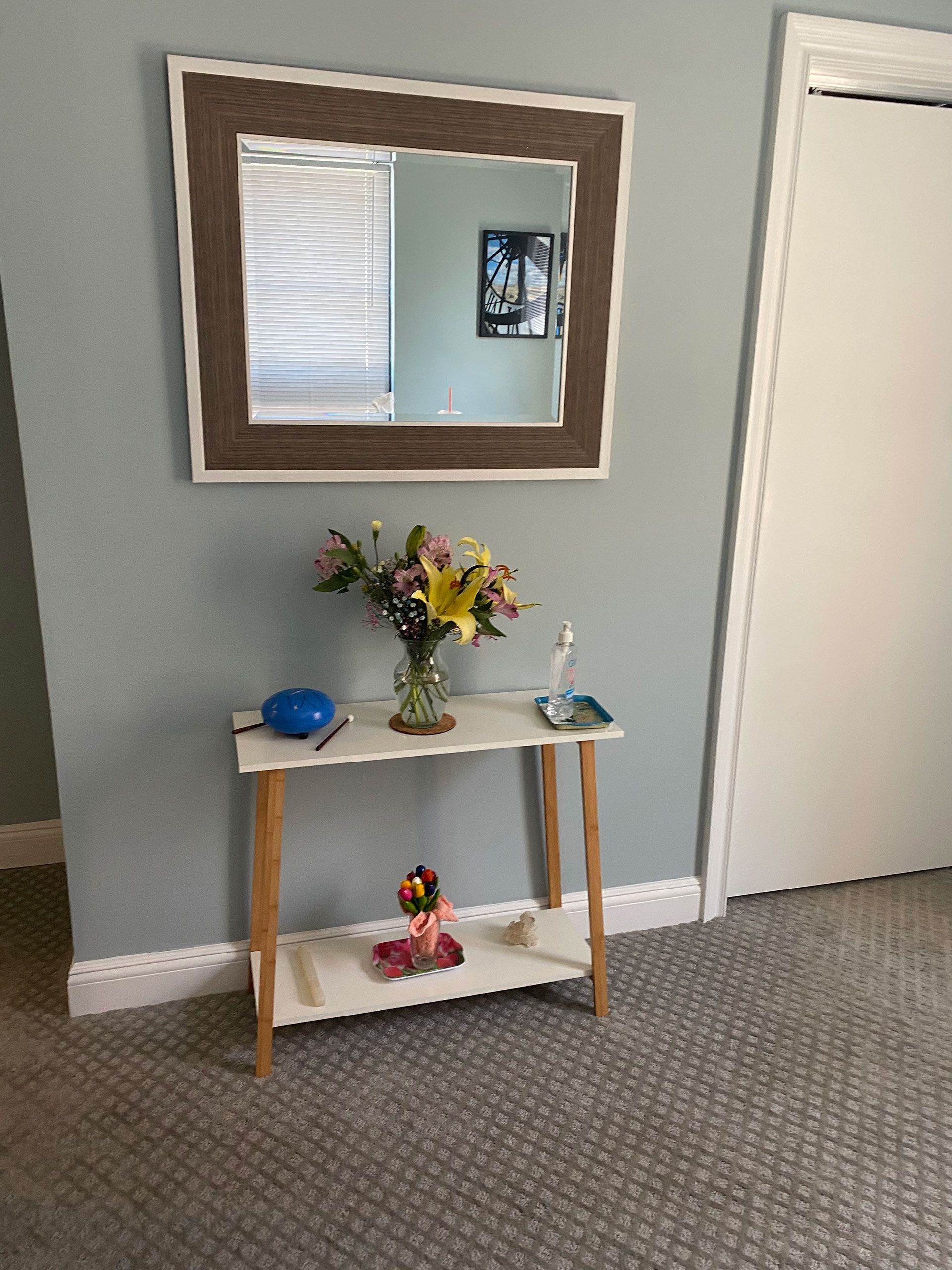 A table with a vase of flowers on it and a mirror on the wall