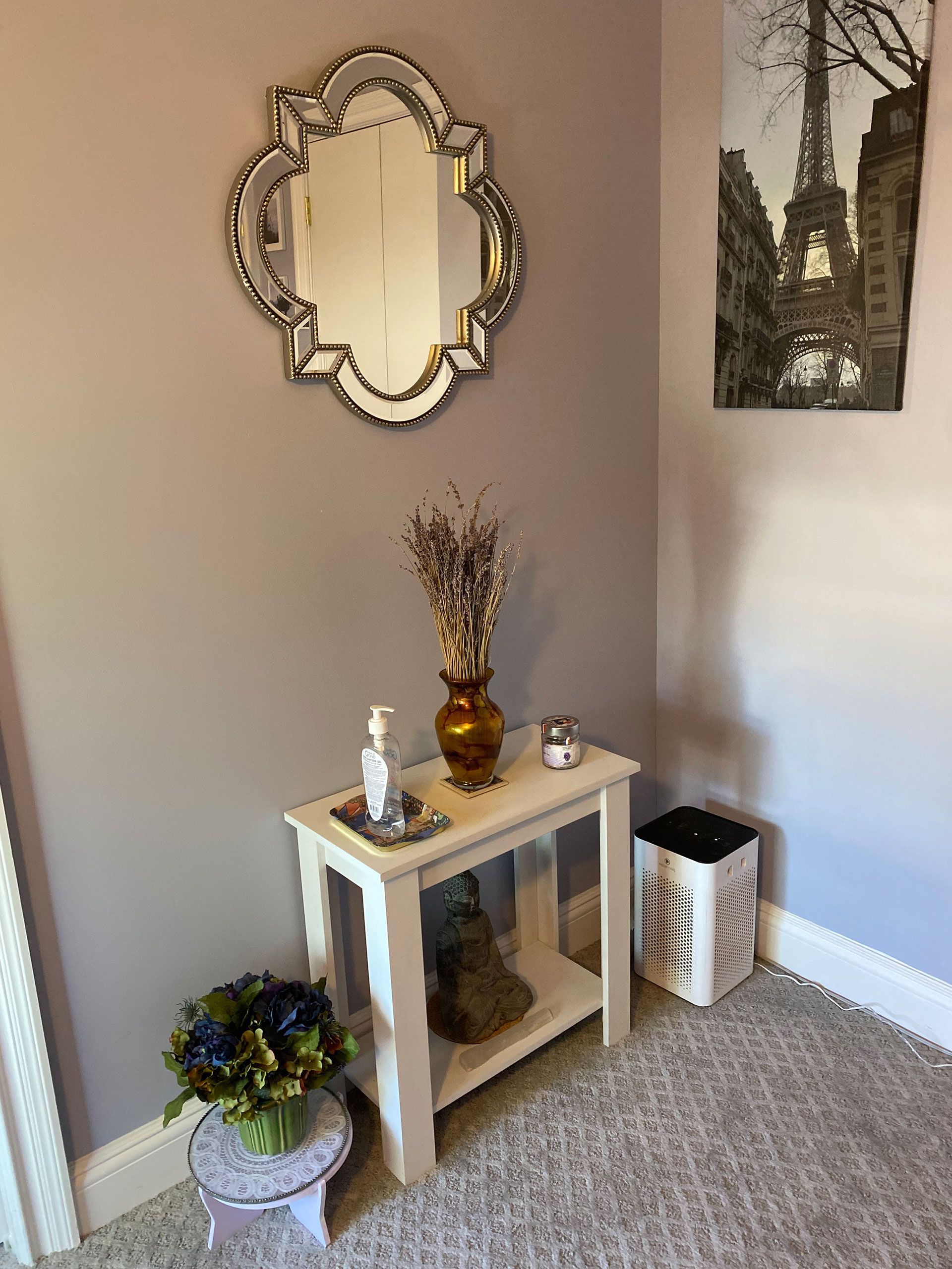 A room with a table, mirror, vase of flowers and a picture of the Eiffel Tower on the wall