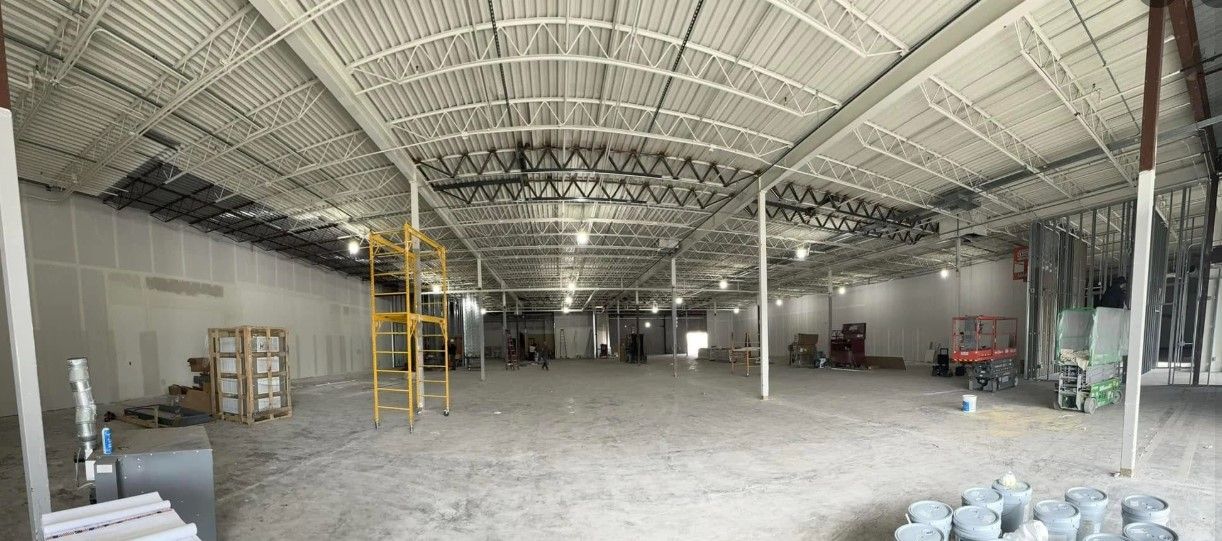 A large empty warehouse with a roof that is being built.