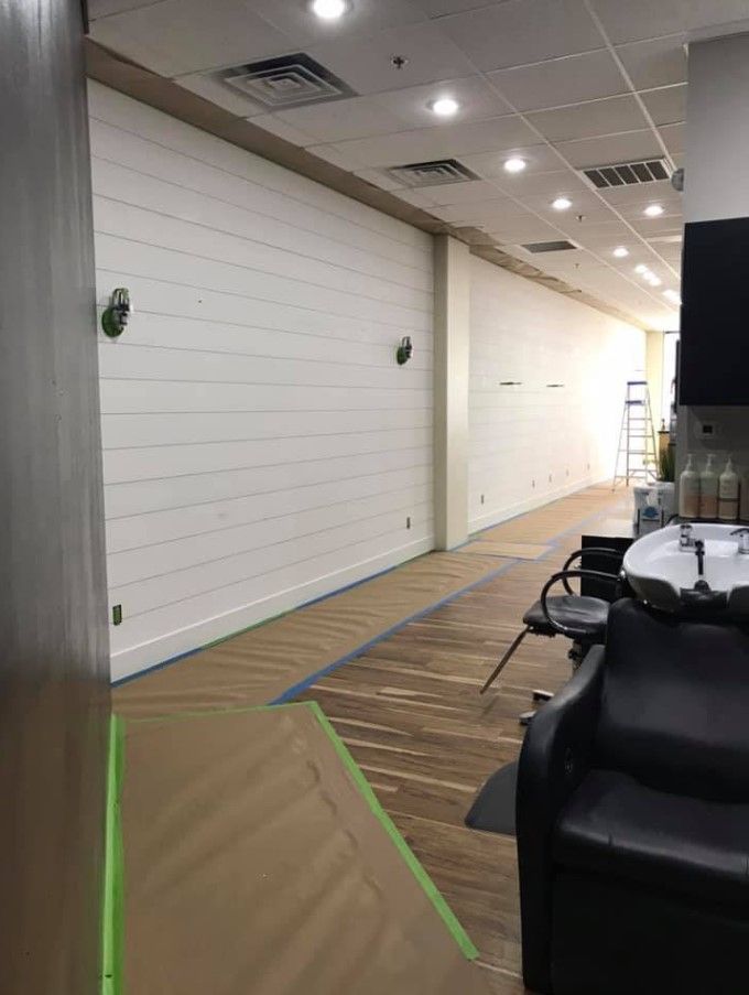 A long hallway in a salon with white walls and a sink.