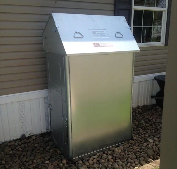 Outdoor metal cabinet with a sloped lid beside a house wall and window