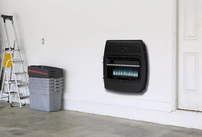 Garage wall with a black wall heater, ladder, and stacked storage bins on the left.