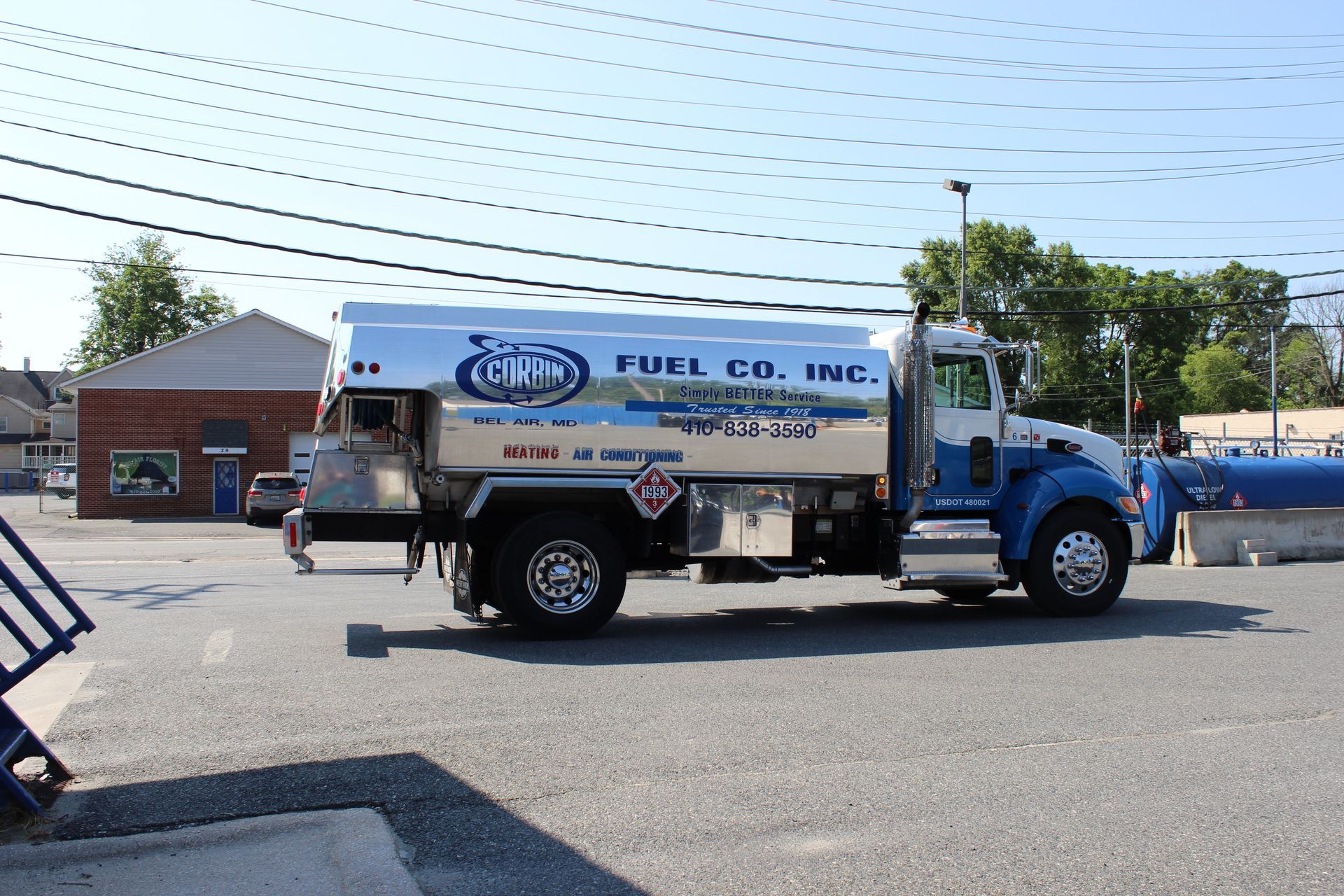Blue and white fuel delivery truck parked on a sunny street beside a building