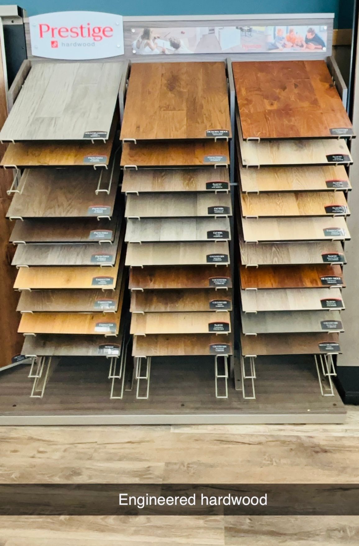 Flooring samples on display rack. Engineered hardwood in various colors: beige, brown, and tan.