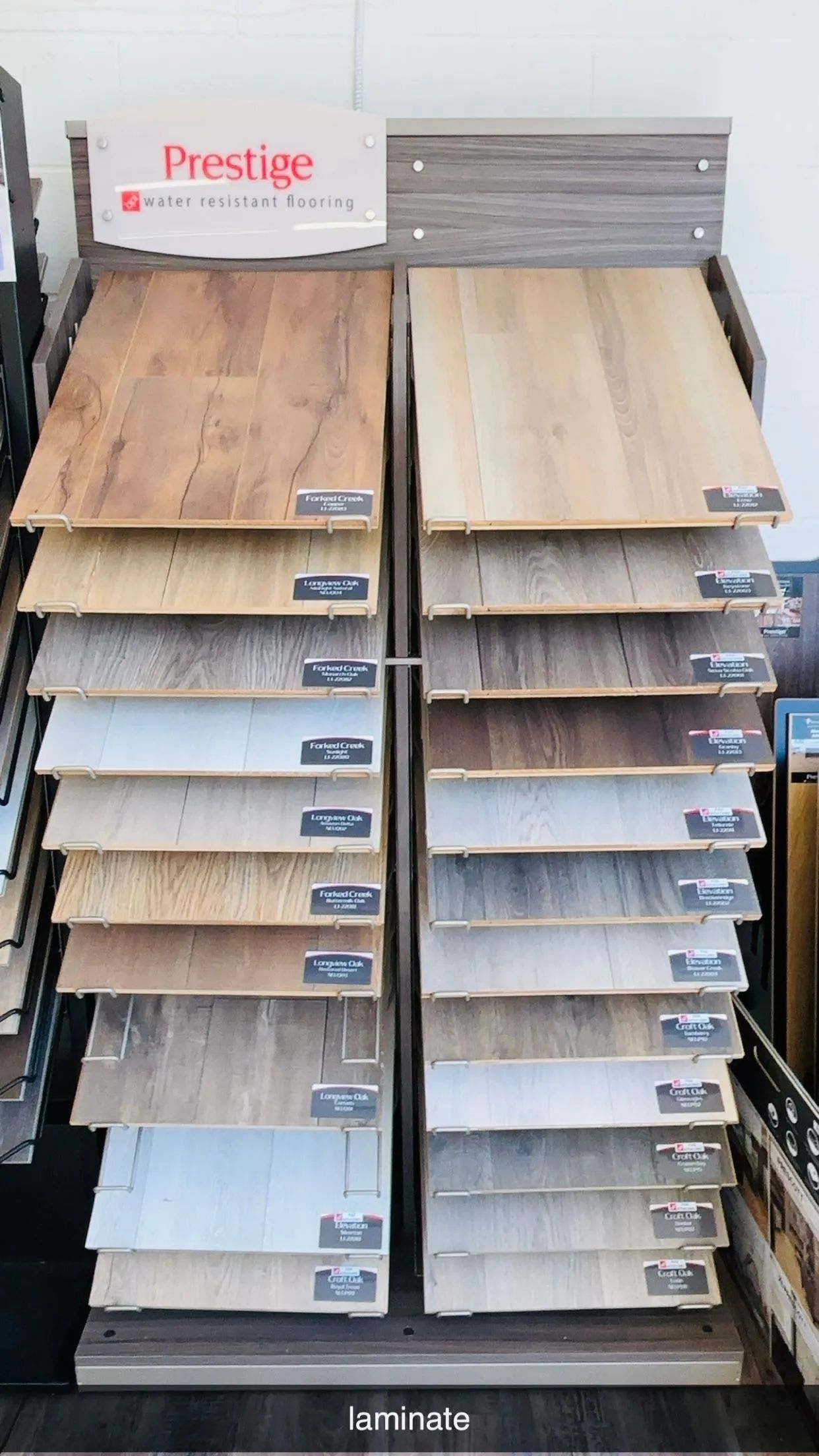Flooring display stand with samples of different wood-look laminate flooring in various colors.