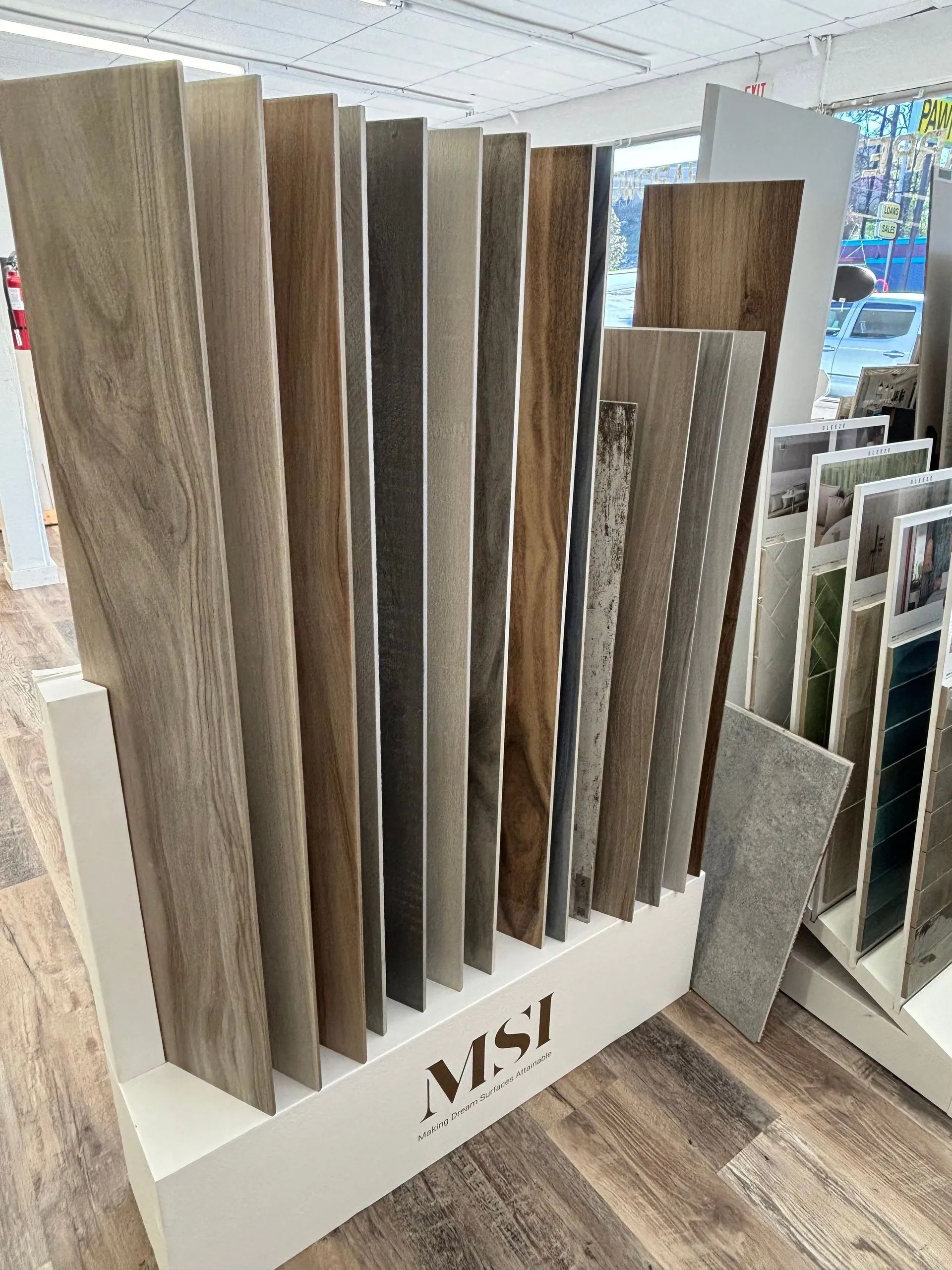 Display of various wood-look tile samples in a retail setting, showcasing different colors and textures.
