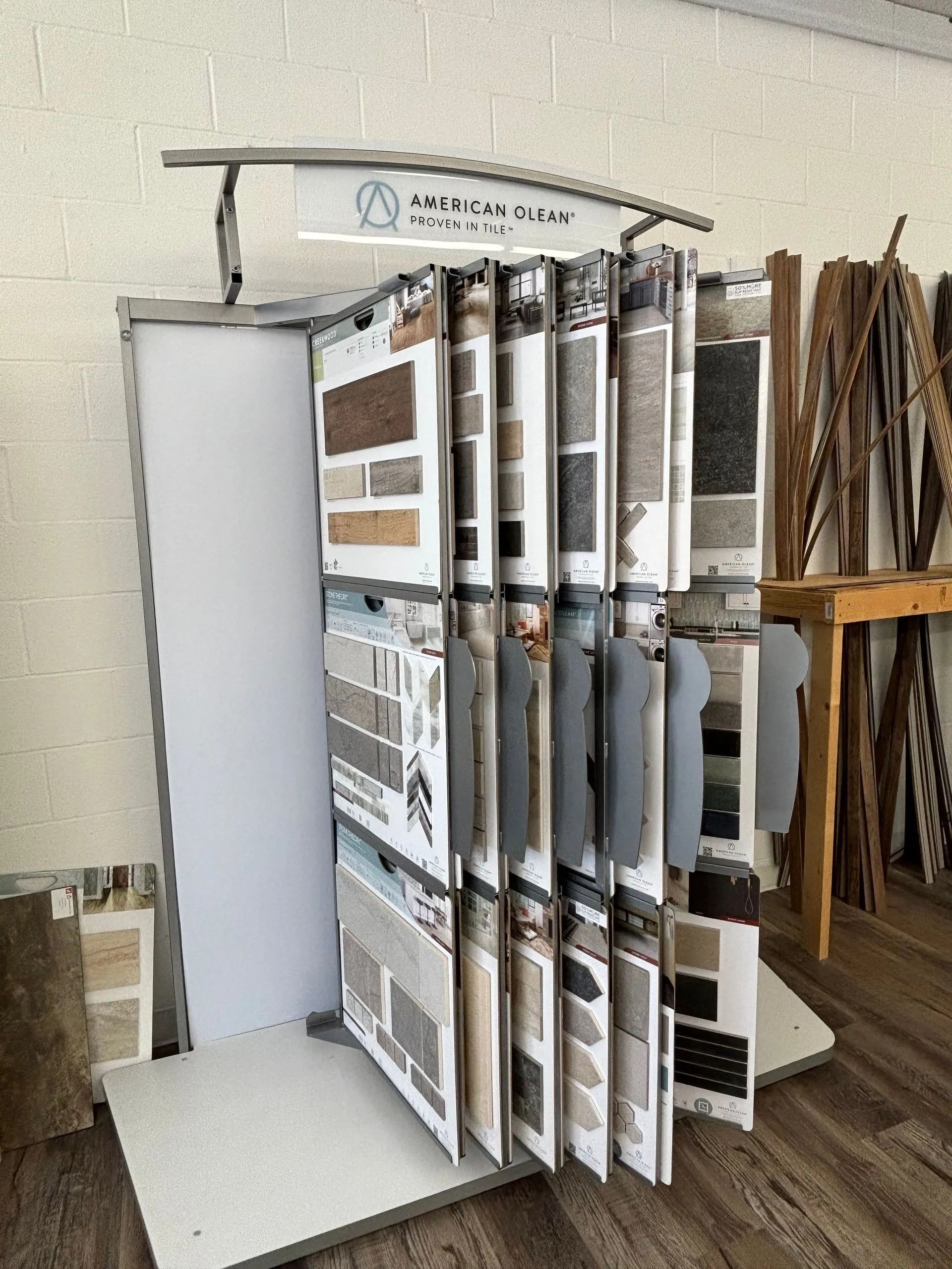 Display of flooring samples in a store, including wood and tile, organized in a rotating rack.