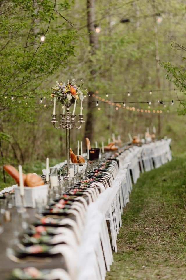 A long wooden table topped with trays of food and plates