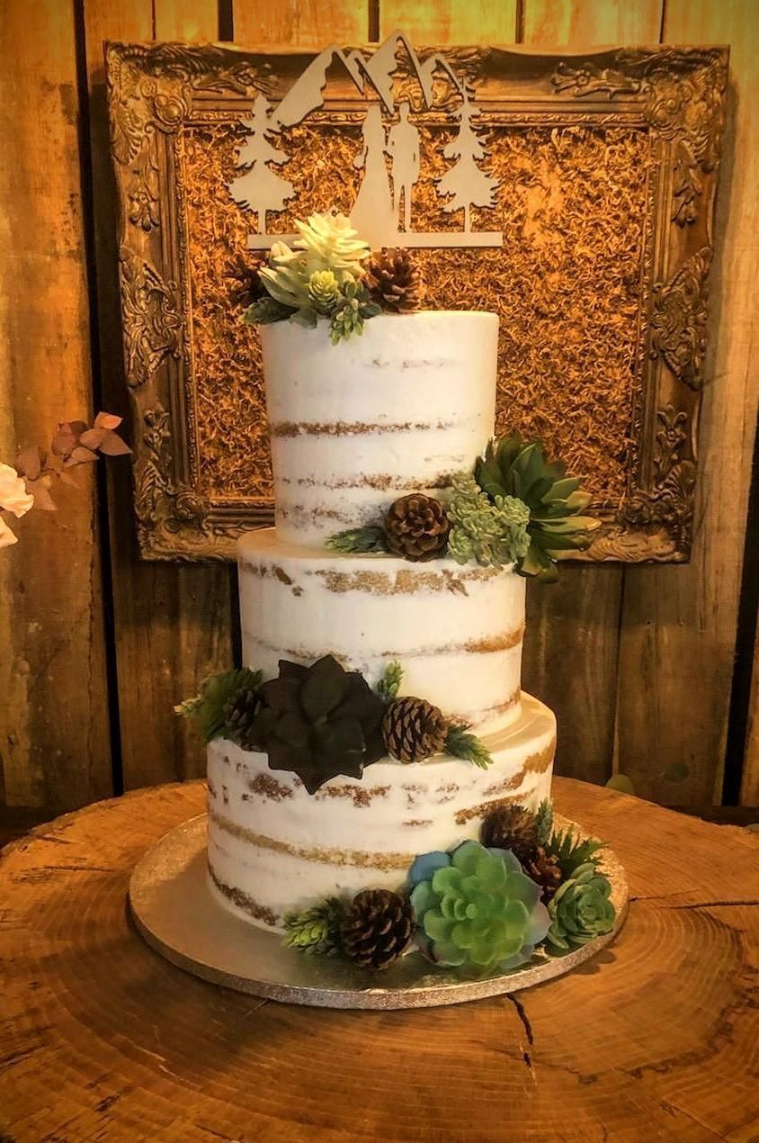 A wedding cake is sitting on top of a wooden table.
