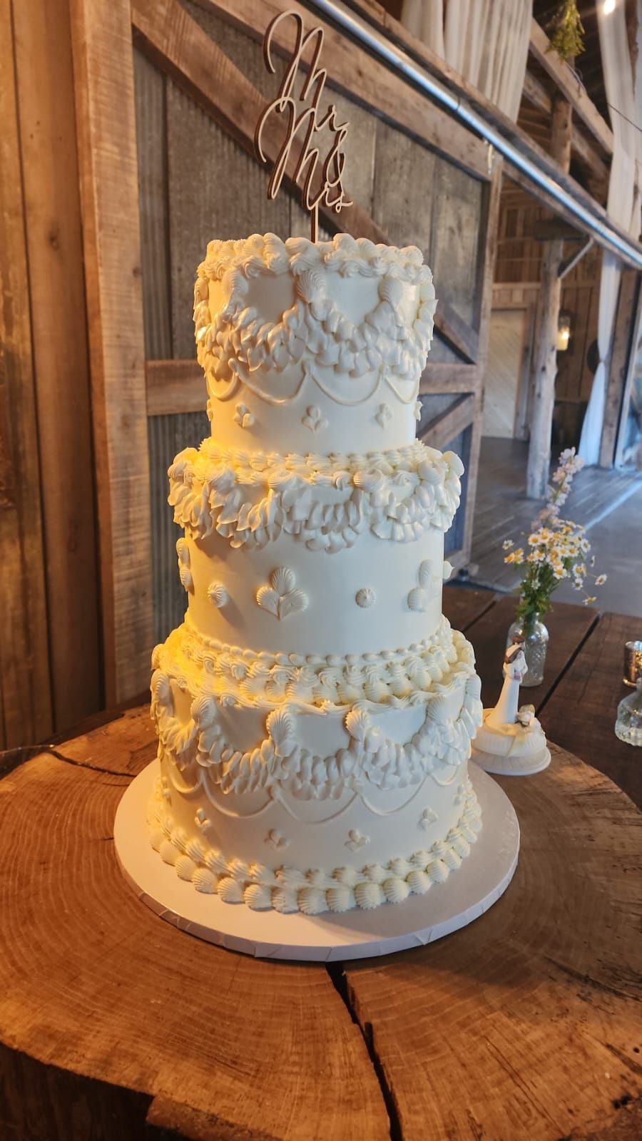 A white wedding cake is sitting on top of a wooden table.