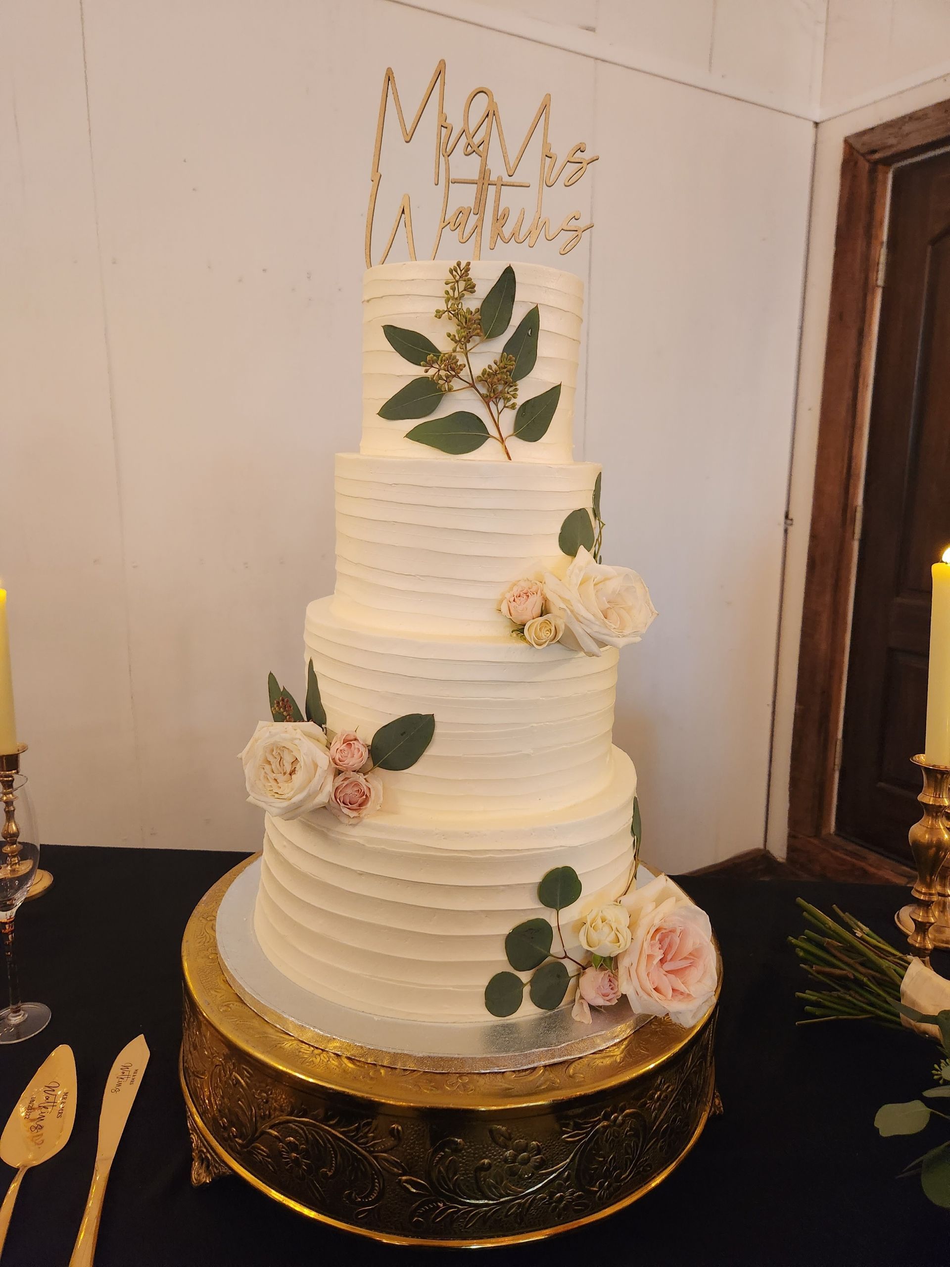 A wedding cake is sitting on a gold cake stand.