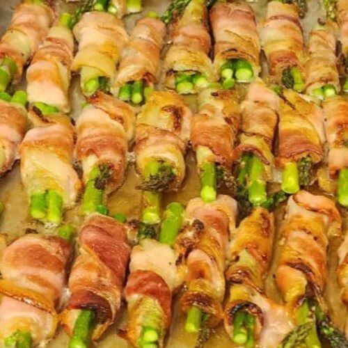 A bunch of asparagus wrapped in bacon on a tray.
