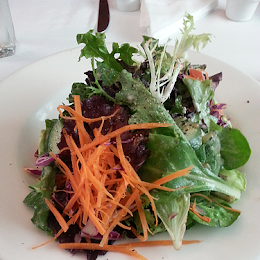 A salad with carrots and lettuce on a white plate