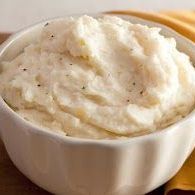 A bowl of mashed potatoes is sitting on a napkin on a table.