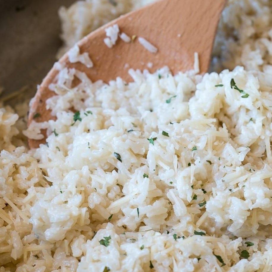 A wooden spoon is in a pile of rice.