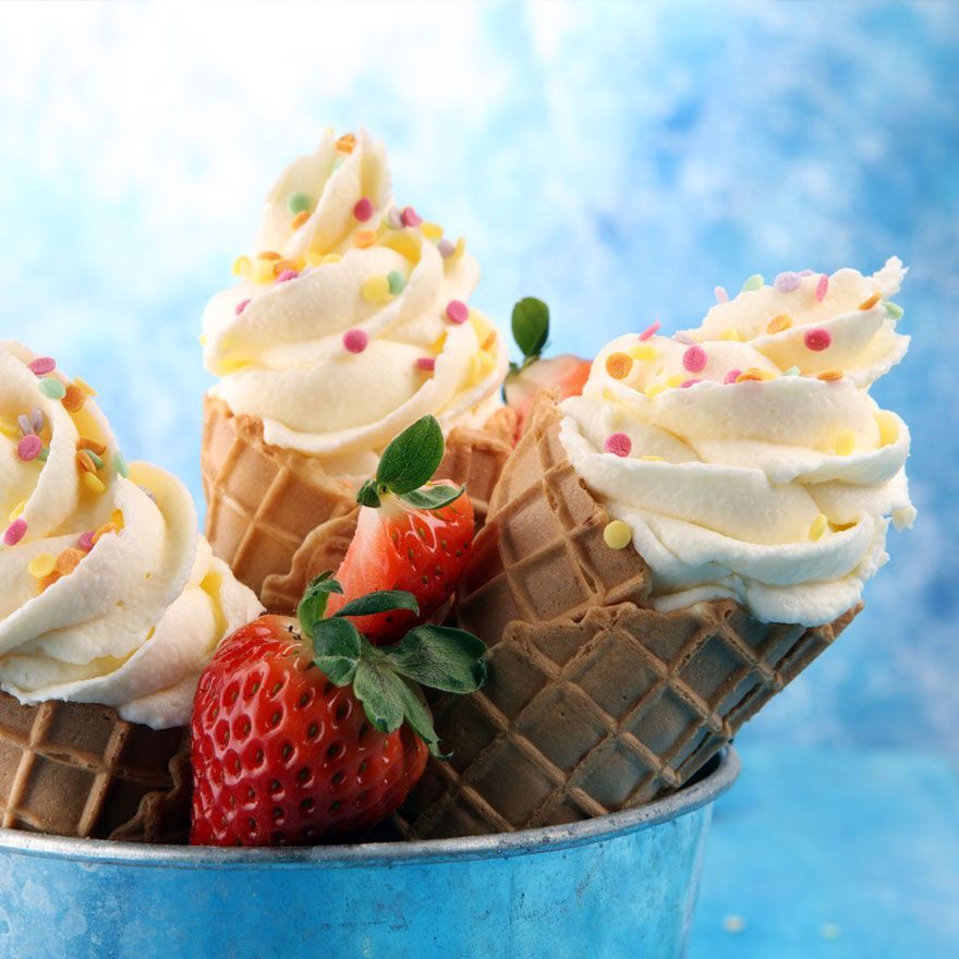 Three ice cream cones with whipped cream and strawberries 