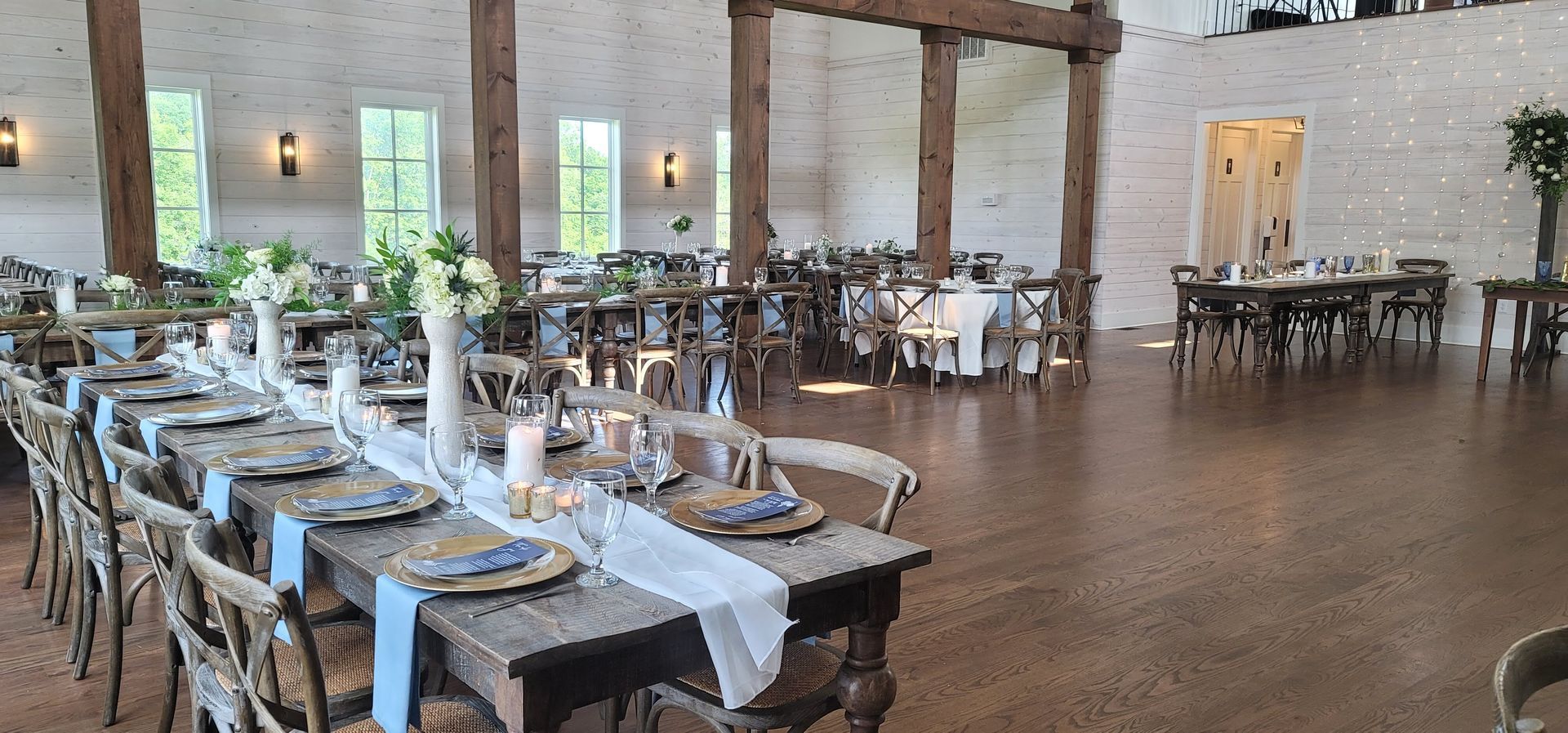A large room with tables and chairs set up for a wedding reception