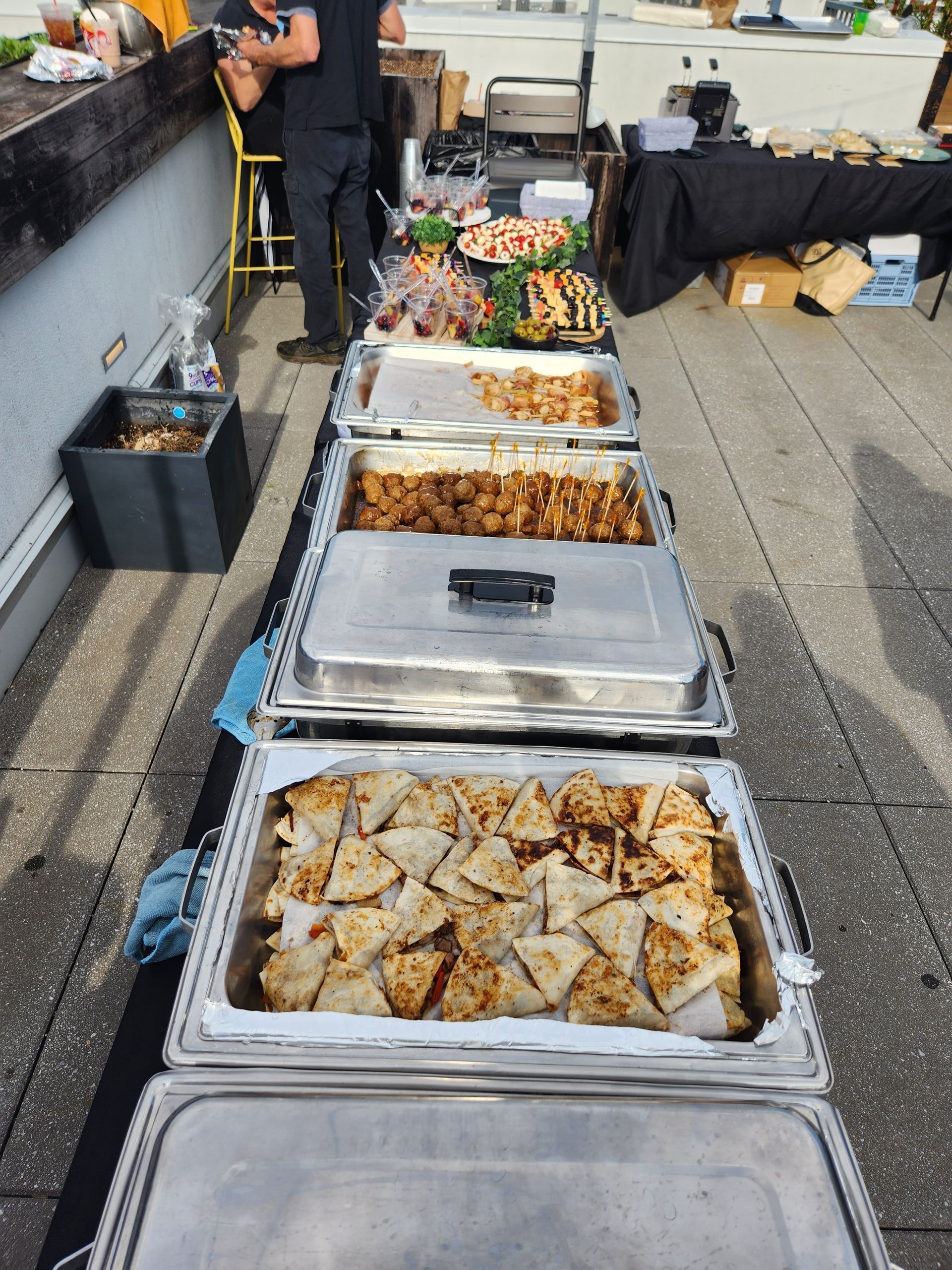 Several trays of food are lined up on a table outside
