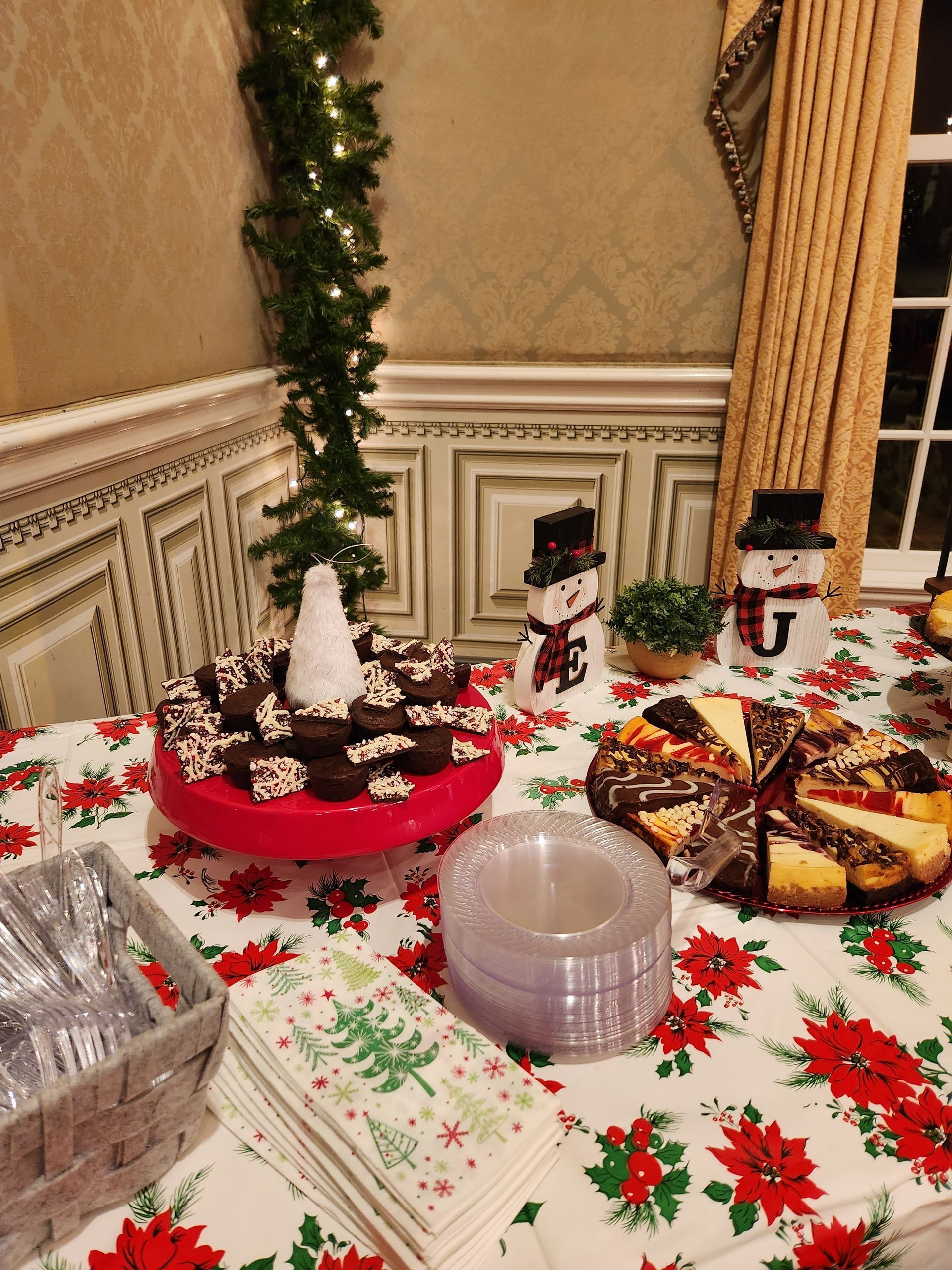 A table with a Christmas tablecloth and a cake on it