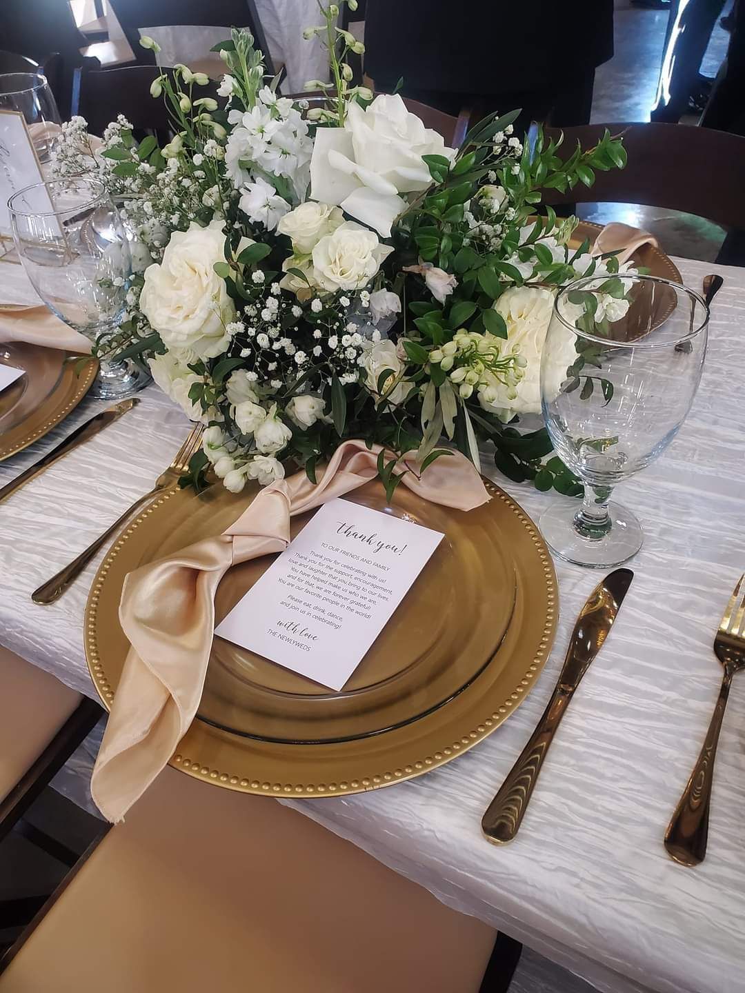 A table set for a wedding reception with plates, silverware, and flowers