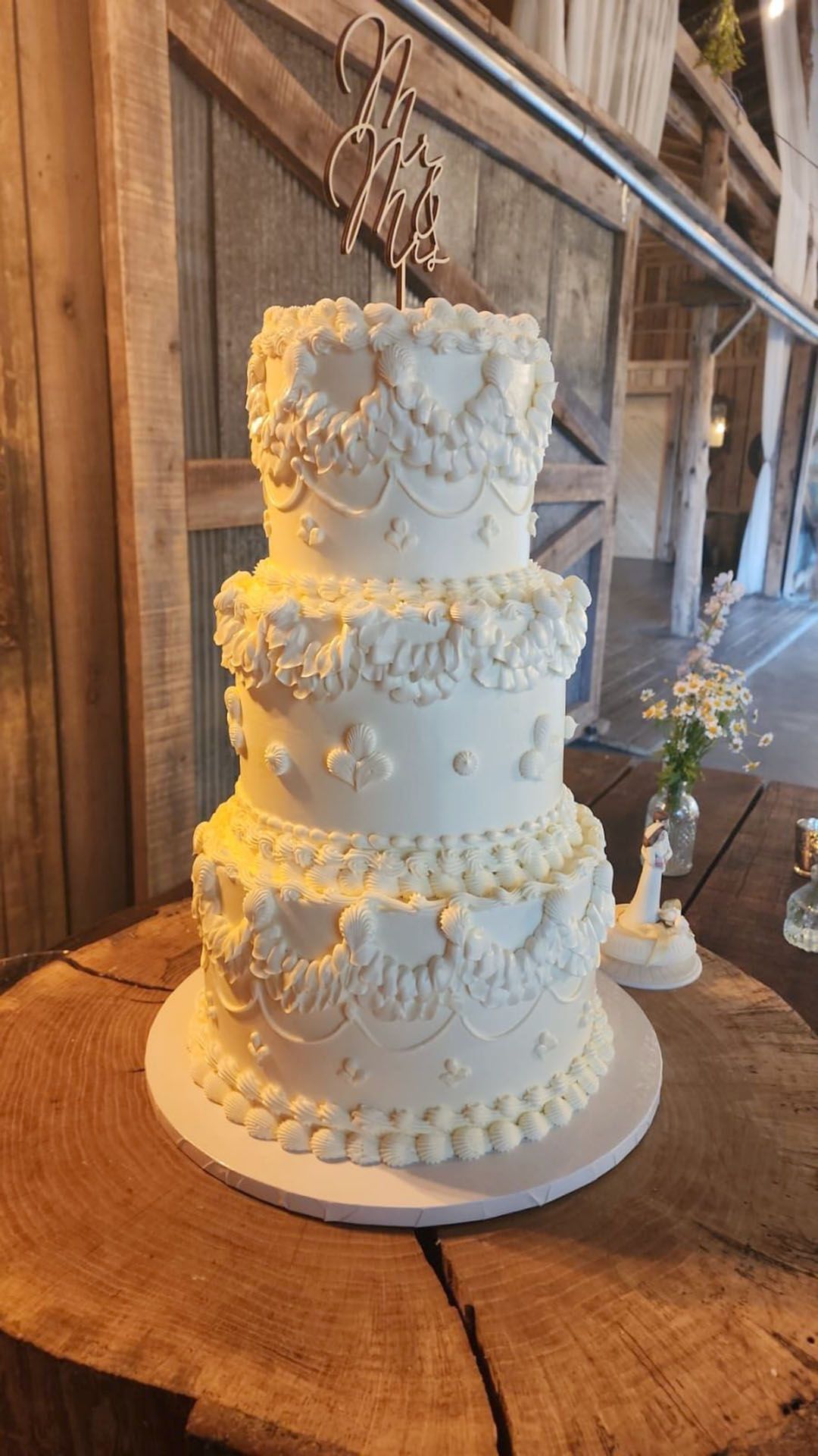 A white wedding cake is sitting on top of a wooden table