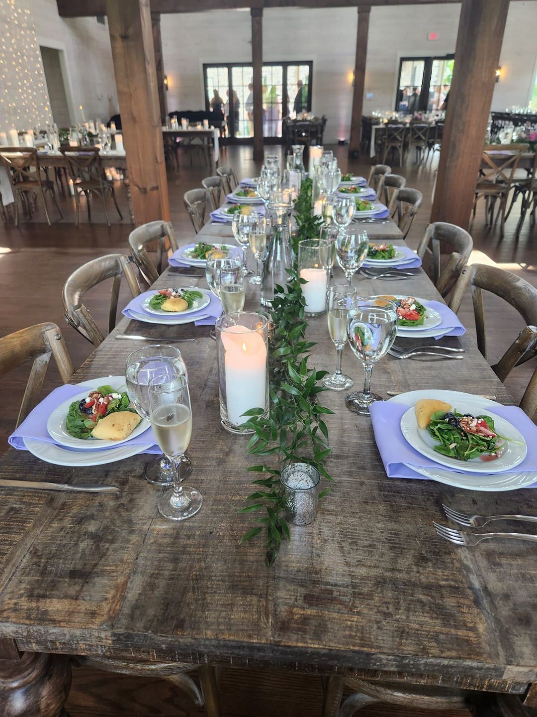 A long wooden table with plates, glasses, and candles on it