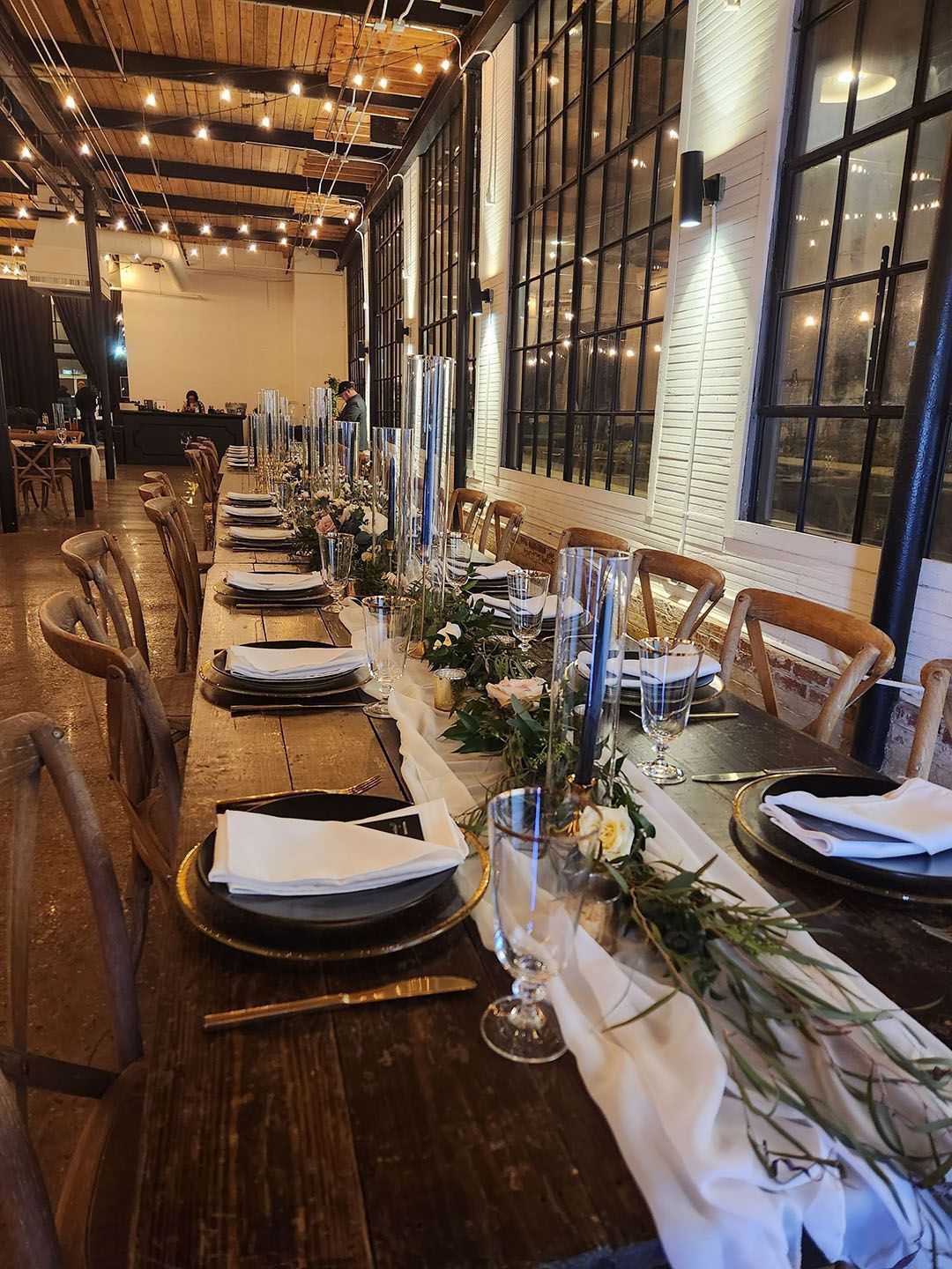 A long wooden table with plates, glasses, and candles on it