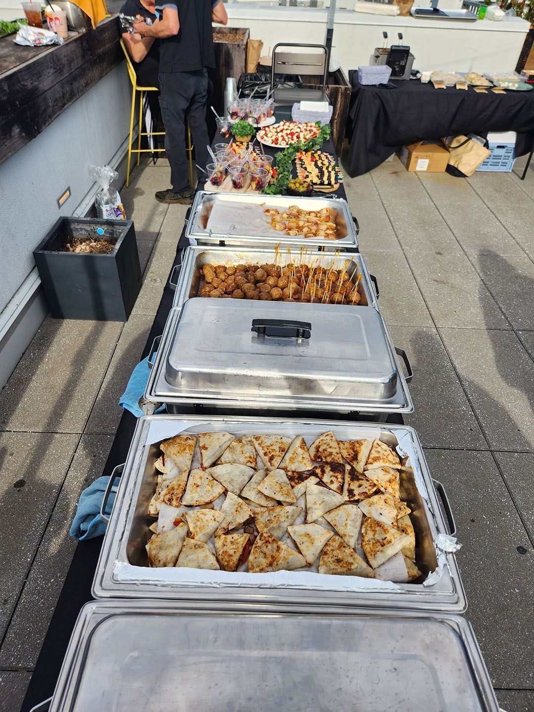A row of trays of food are lined up on a sidewalk