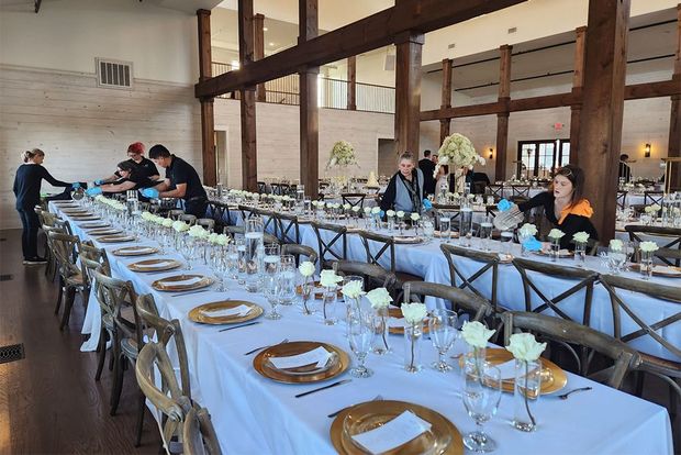 A long wooden table topped with trays of food and plates