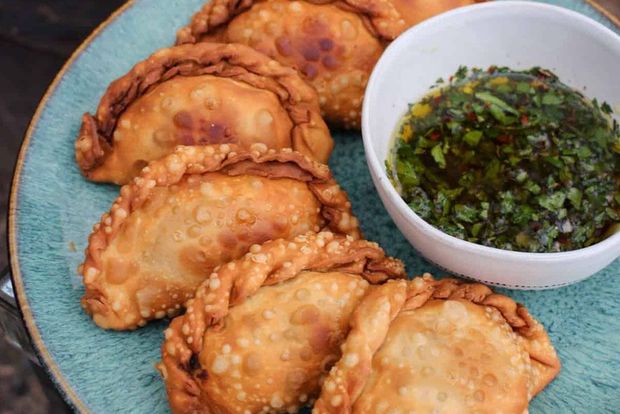 A plate of empanadas with a bowl of dipping sauce