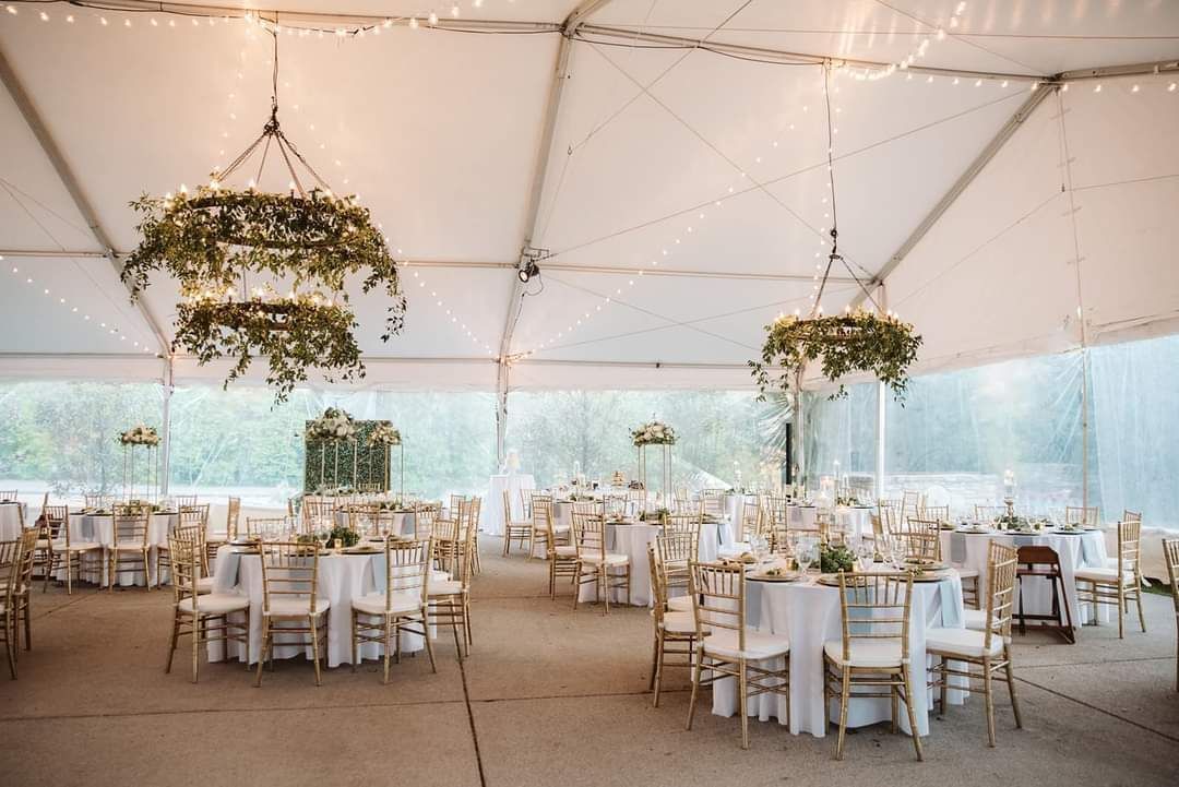 A large tent with tables and chairs set up for a wedding reception
