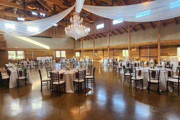 A large room with tables and chairs set up for a wedding reception